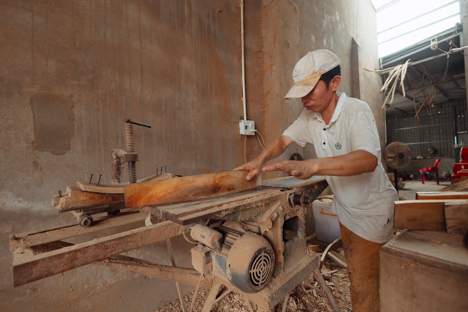 Experienced woodworker carefully inspecting a piece of timber in a sunlit workshop