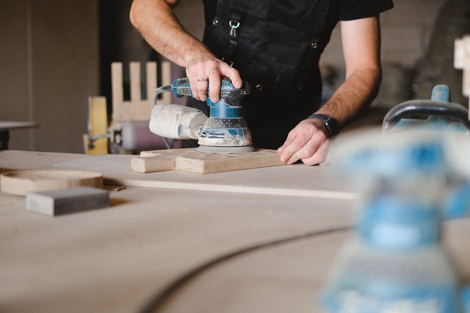Artisan sanding a custom wooden table surface in a workshop